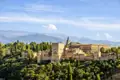 Auf unserer Rundreise durch Andalusien haben wir einen Panoramablick auf die Alhambra mit ihren Türmen, Mauern und Gebäuden, eingebettet in die Landschaft der Sierra Nevada.