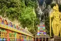 Sie besuchen die goldene Statue des Hindu-Gottes Murugan, die vor der steilen, regenbogenfarbenen Treppe, die zu den Batu-Höhlen führt, wacht.