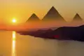 Die majestätischen Pyramiden von Gizeh in Ägypten bei einem stimmungsvollen Sonnenuntergang über dem glitzernden Nil.