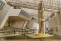 Reisende bestaunen die riesige Pharaonenstatue in der modernen, lichtdurchfluteten Halle des Grand Egyptian Museum in Kairo.