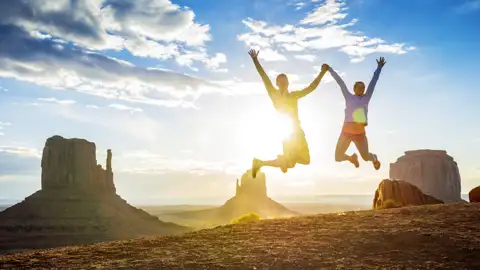 Junge Traveller springen freudig in die Luft vor dem Hintergrund des Monument Valley, ein Highlight dieser Rundreise durch den Westen der USA.