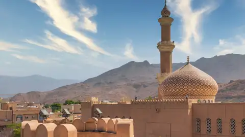 Auf Ihrer individuellen Rundreise durch den Oman sehen Sie in Nizwa den Turm des Forts, das höchste Gebäude in Nizwa: Der Blick schweift über die Neu- und die Altstadt, die Gärten und Lehmhäuser bis hinüber zu den Bergen.