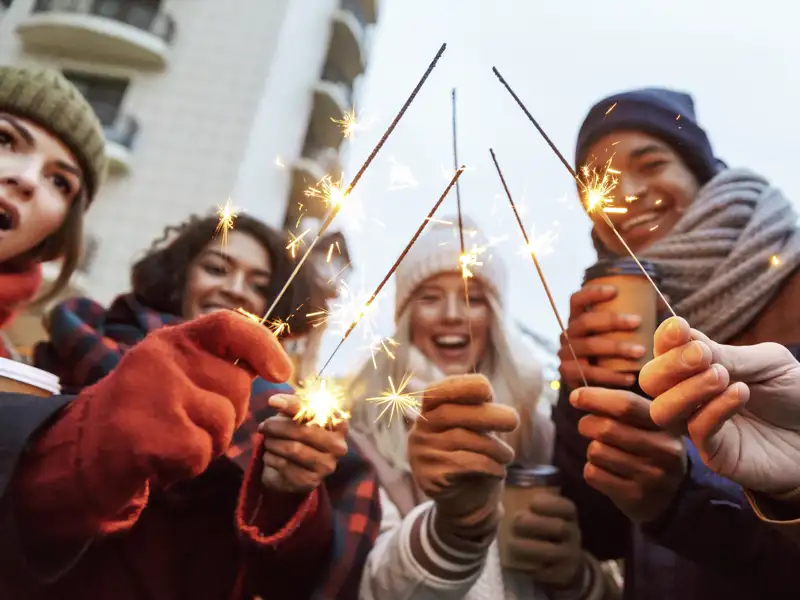 Eine Gruppe junger Reisender feiert mit Wunderkerzen Silvester in Helsinki