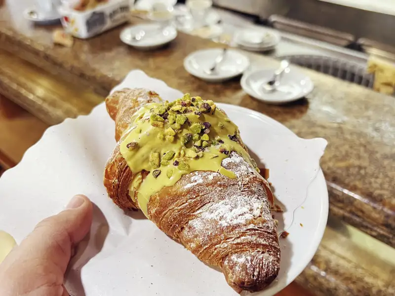 Ein frisches Pistazien-Cornetto, bereit zum Genießen in einer Kaffeebar während einer Gruppenreise für junge Leute in Rom.