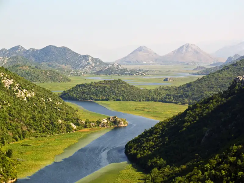 Am 3. Tag der Marco Polo Rundreise in kleiner Gruppe durch Montenegro spazieren wir am Fluss entlang durch die Hügellandschaft zur alten Brücke in Rijeka Crnojevica.