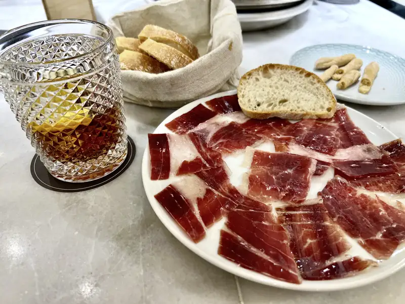 Genießen Sie spanische Tapas auf Ihrer Reise durch Andalusien, z.B. Schinken, Brot und Wermut.