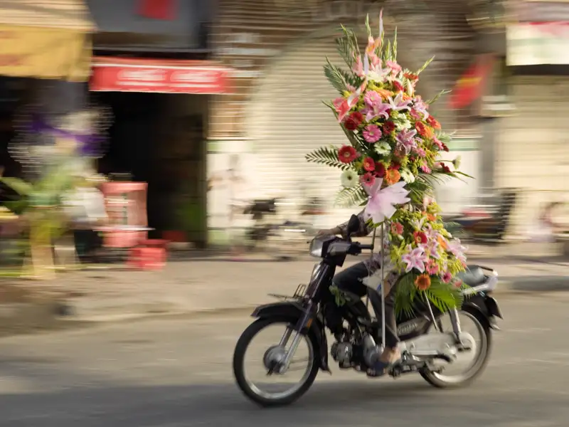 In Saigon ist das Treiben immer bunt und alles wird auf Vespas oder Mofas transportiert, so auch Blumen.