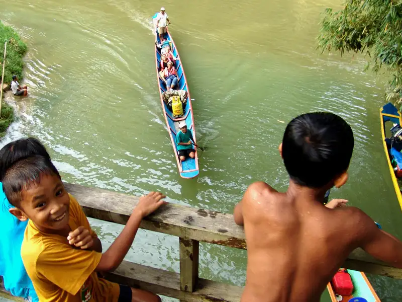 Spaß auf dem Wasser - Kinder des Volkes Iban in Sarawak beim Baden und Begrüßen von Touristen.