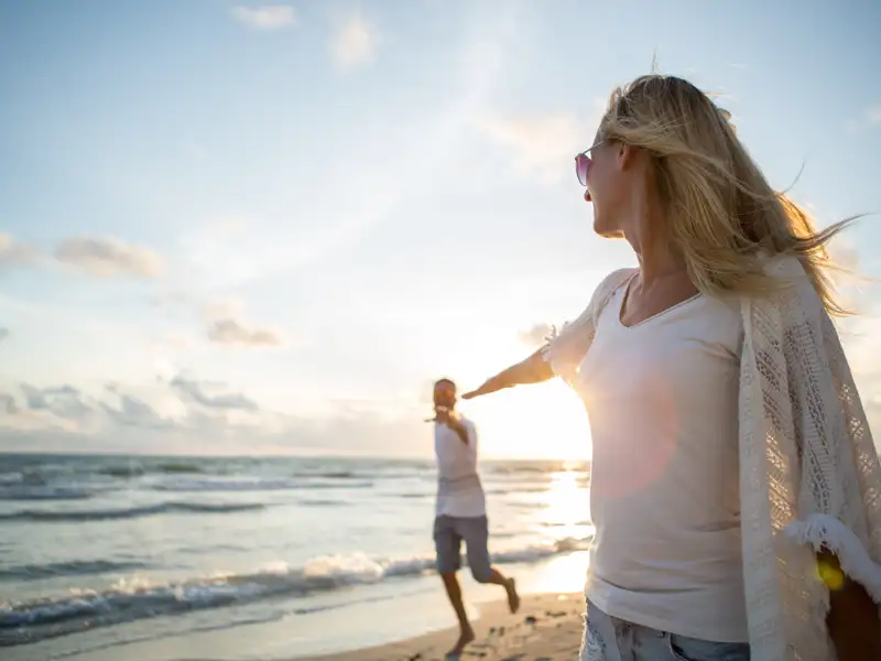 Ein Paar genießt den Badeaufenthalt am Strand auf Cayo Santa Maria bei Sonnenuntergang. Ein Strand wie im Bilderbuch: feinsandig, palmengesäumt und kristallklares Wasser. Abends im Hotel gibt's fangfrischen Fisch, kühle Drinks und heiße Rhythmen zum Sonnenuntergang.