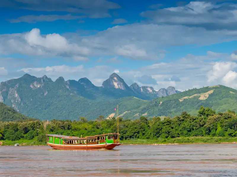 Bei unserer Reise empfängt uns unser laotischer Scout und nimmt uns mit auf ein traditionelles Mekongboot. Wir gleiten den mächtigen Strom hinab und betrachten die wilde grüne Landschaft an seinem Ufer.