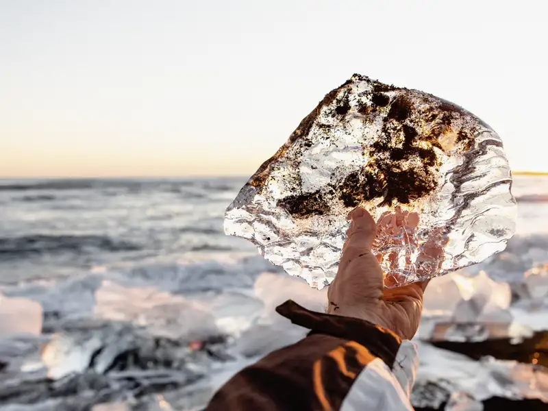 Auf unserer YOUNG LINE Rundreise durch Island im Winter fahren wir zum Diamond Beach, wo unzählige Eisblöcke auf dem schwarzen Sand glitzern.