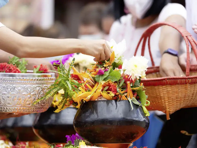 In einem Tempel in Thailand werden bunte Blumen als Opfergaben arrangiert. Diese und andere Szenen erleben wir auf unserer Rundreise durch Südthailand immer wieder.