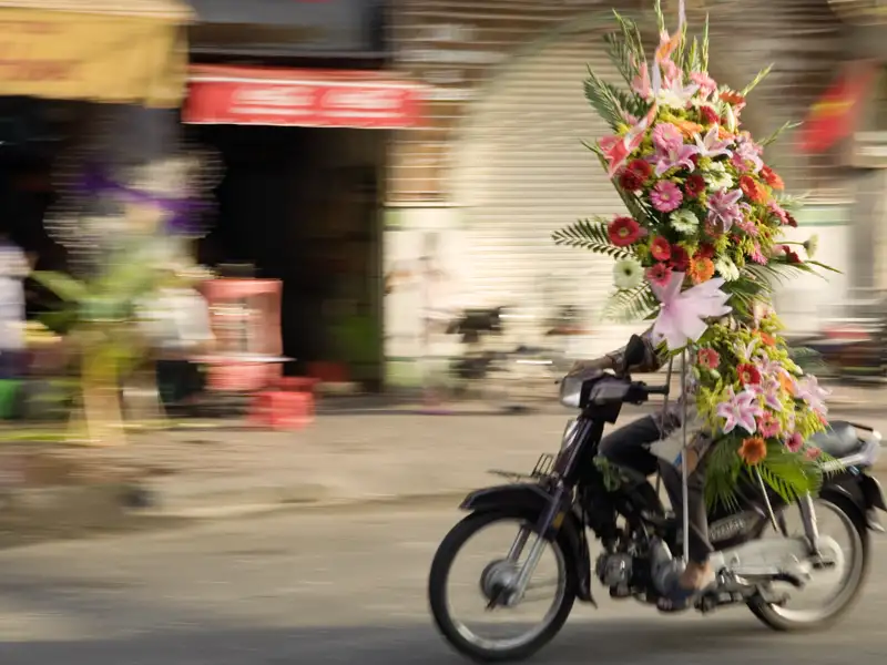 In Saigon ist das Treiben immer bunt und alles wird auf Vespas oder Mofas transportiert, so auch Blumen.