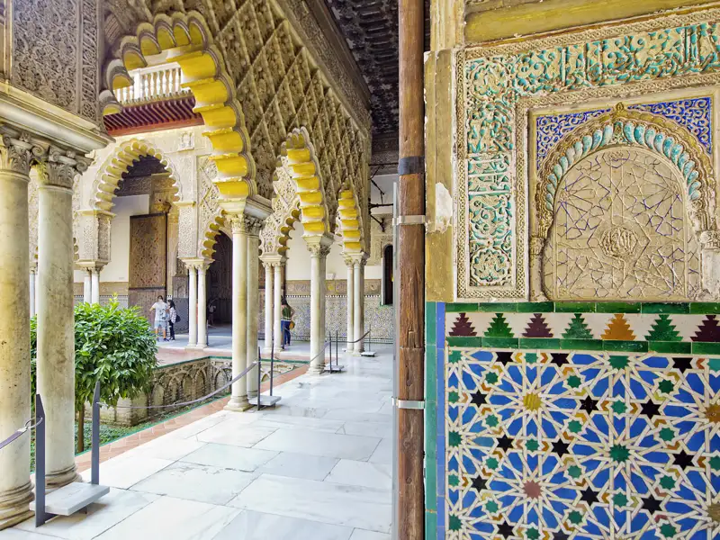 Auf Ihrer individuellen Rundreise im Mietwagen durch Andalusien bewundern Sie die kunstvollen Säulen, Bögen und dekorativen Fliesen im Innenhof des Palastes Real Alcázar in Sevilla