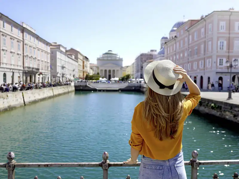 Reisende am Kanal mit Blick auf die Stadt Triest. Auch Sie haben bei Ihrer Reise Gelegenheit eine Blick zu wagen.