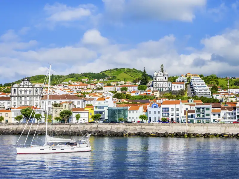 Auf unserer Rundreise besuchen wir die Hafenstadt Horta auf der Azoreninsel Faial mit traditioneller Architektur und einem Segelboot.