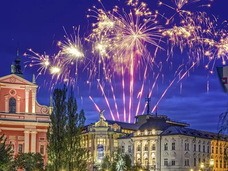 Festliches Silvester-Feuerwerk über dem Preseren-Platz und der rosaroten Franziskanerkirche in Ljubljana bei Nacht.