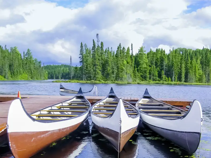 Auf Ihrer Rundreise sehen Sie Kanus am Wasser.