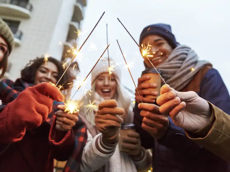 Eine Gruppe junger Reisender feiert mit Wunderkerzen Silvester in Helsinki