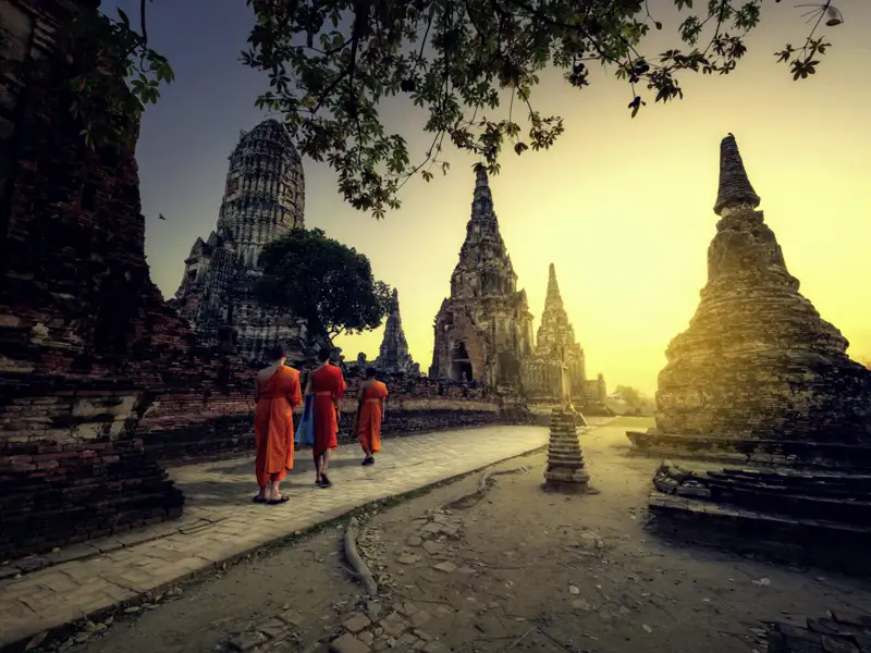 Mystisch sieht es aus, wenn die Mönche zum Sonnenaufgang durch die Tempelruinen der früheren Hauptstadt Ayutthaya marschieren.