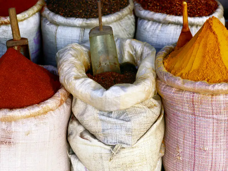Nahaufnahme von Säcken mit leuchtend rotem Paprika- und gelbem Kurkumapulver auf einem Markt, ein typischer Anblick beim  Besuch lokaler Basare während der Rundreise.
