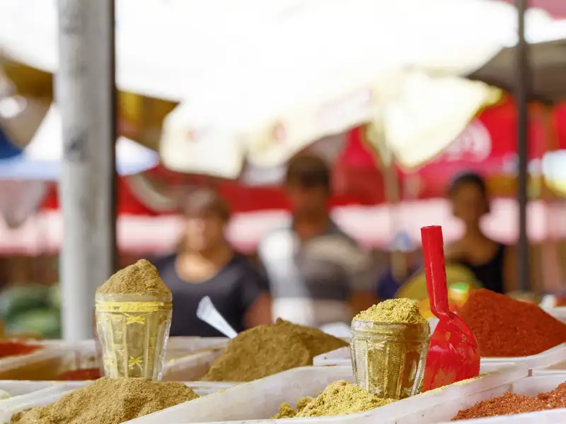 Bunte, gemahlene Gewürze in Gläsern und Haufen auf einem lebhaften Bauernmarkt in Georgien.