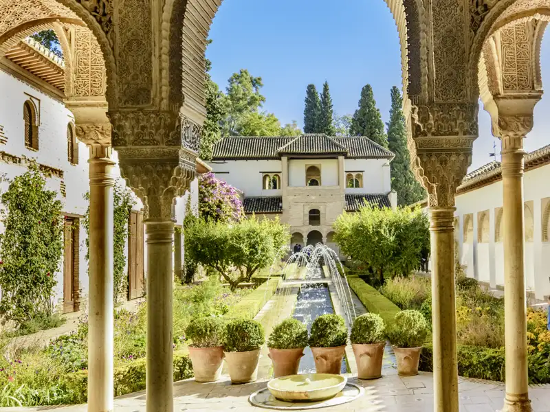 Ein Highlight auf unserer Rundreise durch Andalusien: Die kunstvollen Bögen und Säulen der Alhambra rahmen den Blick auf den Garten und den Brunnen ein.