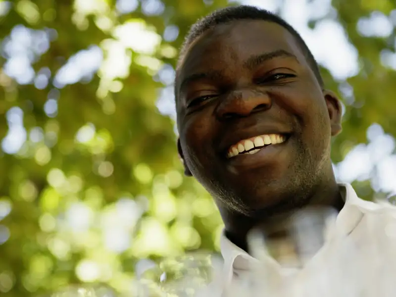 Ein Afrikaner, lachend vor Weinreben