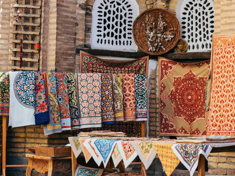 Bunte handgefertigte Teppiche und Stoffe auf einem Markt in Usbekistan.