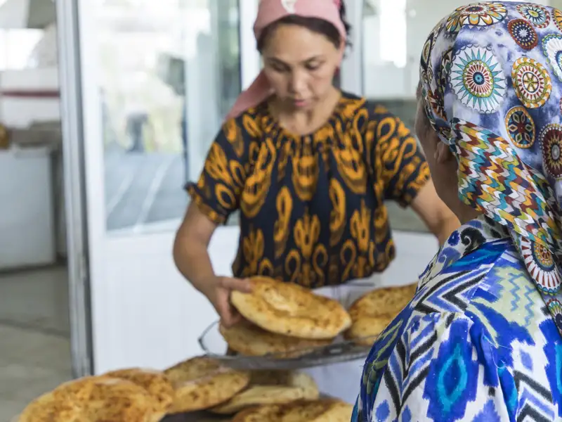 Eine Frau backt traditionelles Brot in einer Bäckerei in Usbekistan.