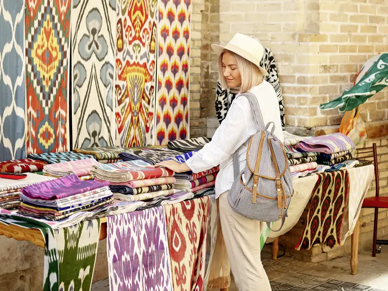 Eine Frau betrachtet bunte Stoffe auf einem Markt.