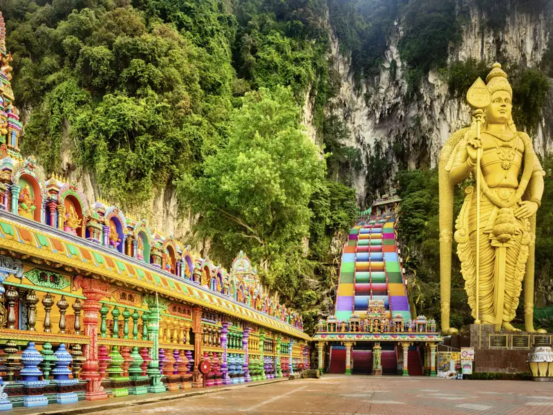 Sie besuchen die goldene Statue des Hindu-Gottes Murugan, die vor der steilen, regenbogenfarbenen Treppe, die zu den Batu-Höhlen führt, wacht.