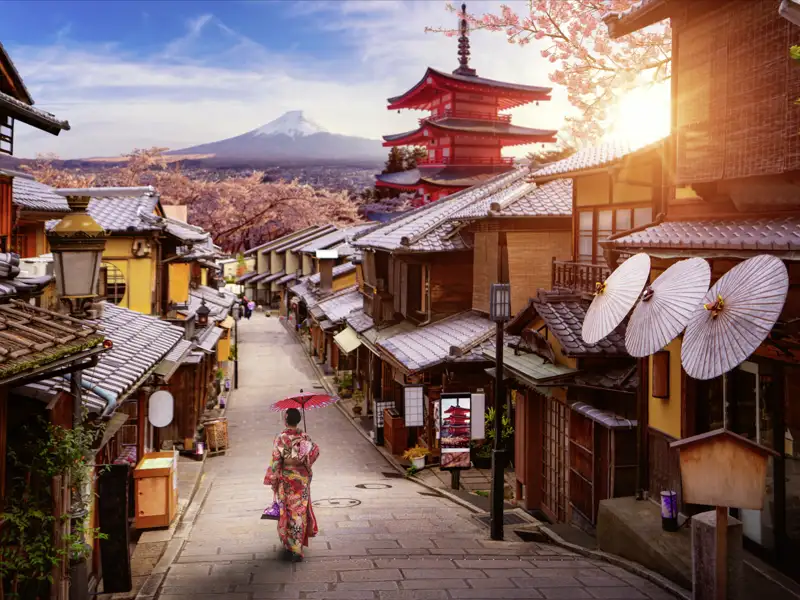 Malerische Gasse in Japan: Frau im Kimono mit Schirm, im Hintergrund rote Pagode, Kirschblüten und der heilige Berg Fuji.