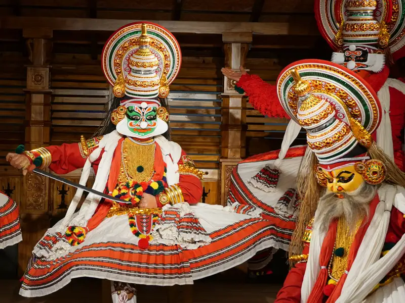 Aufführung eines Kathakali-Tanzes in Kochi  bei dem die Tänzer in bunte Kostüme mit verzierten Masken gekleidet sind.