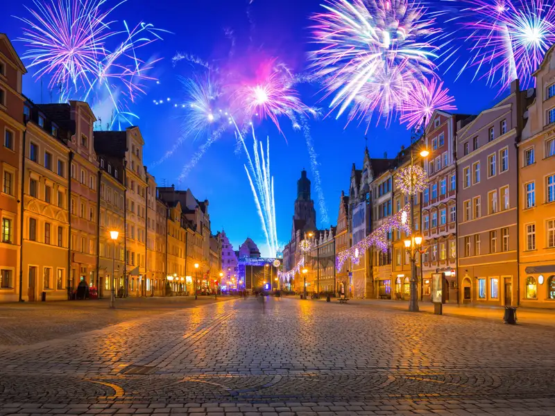 Farbenfrohes Silvester-Feuerwerk über dem beleuchteten Marktplatz in Breslau mit seinen historischen Häuserfassaden.
