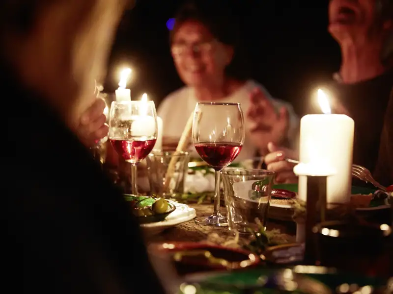 Stimmungsvolles Silvester-Dinner einer Reisegruppe bei Kerzenschein mit Rotwein in einem Restaurant.