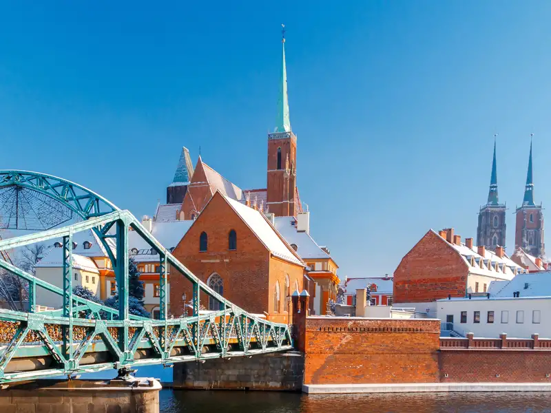 Die grüne Most Tumski Brücke führt über die Oder zur verschneiten Dominsel in Breslau an einem sonnigen Wintertag.