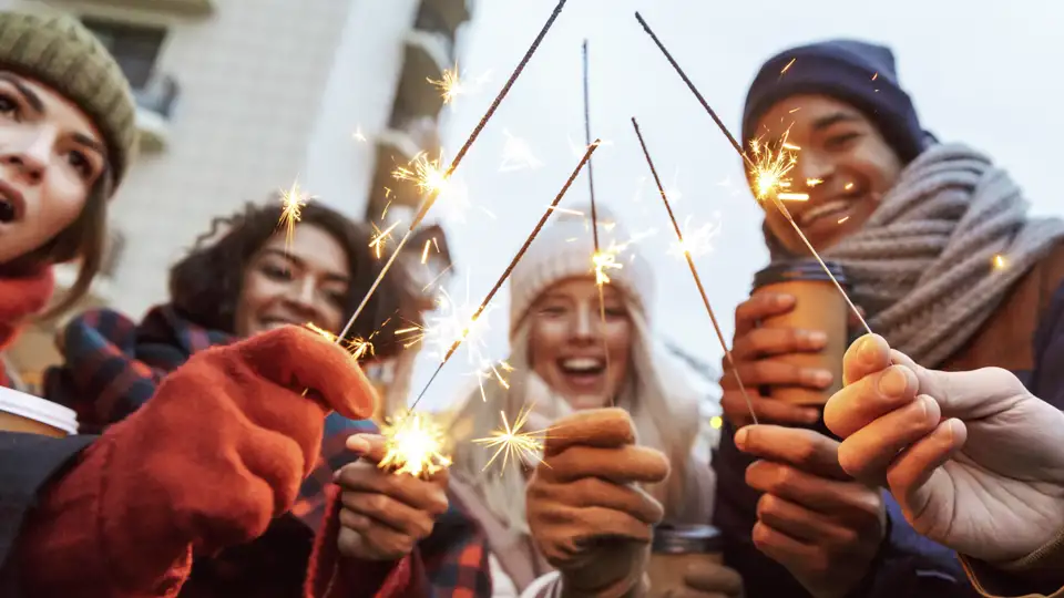 Eine Gruppe junger Reisender feiert mit Wunderkerzen Silvester in Helsinki
