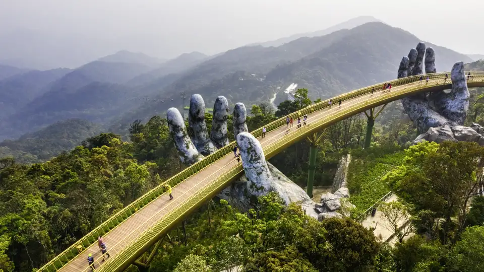 In den Bergen Zentralvietnams schreiten junge Traveller ab 35 gemeinsam über die spektakuläre Golden Bridge.