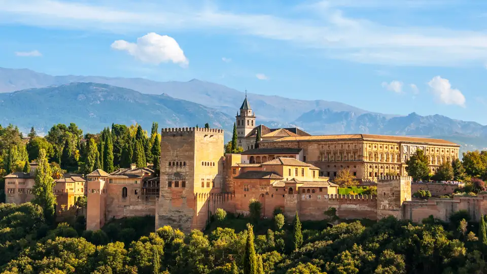 Auf Ihrer individuellen Rundreise im Mietwagen durch Andalusien haben Sie einen Panoramablick auf die Alhambra mit ihren Türmen, Mauern und Gebäuden, eingebettet in die Landschaft der Sierra Nevada.