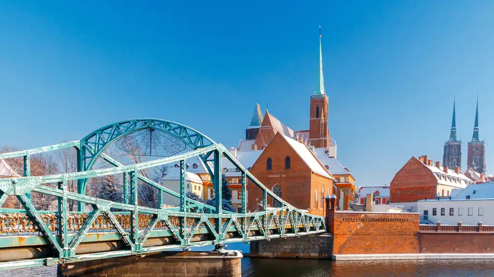 Die grüne Most Tumski Brücke führt über die Oder zur verschneiten Dominsel in Breslau an einem sonnigen Wintertag.