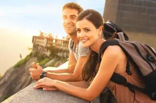 Zwei Personen mit Rucksäcken, die an einem Geländer stehen.